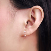 Fine jewellery, silver jewellery, hypoallergenic, tarnish-free, side view Close-up of an ear with small stud earrings with crystal and a silver spherical end.